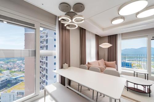 a living room with a couch and a table and windows at Le Collective Busan Gijang in Busan