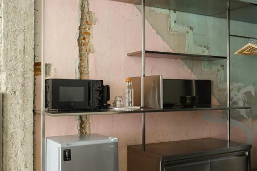 a kitchen with a tv and a refrigerator on shelves at Stupid Stay in Bangkok
