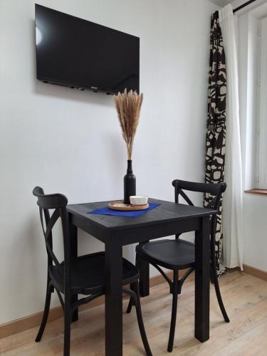 a black dining room table with two chairs and a tv at Chambre NINA in Agen