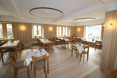 a restaurant with wooden tables and chairs and windows at Schwarzes Kreuz in Teuschnitz