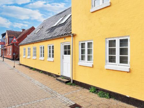 a yellow building with white windows on a street at 4 person holiday home in Ålbæk-By Traum in Ålbæk