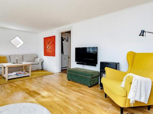 a living room with a yellow couch and a tv at 4 person holiday home in Ålbæk-By Traum in Ålbæk
