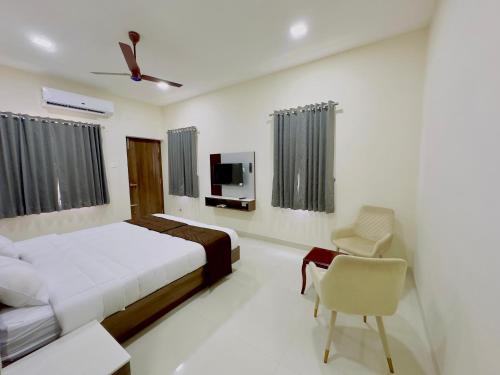 Schlafzimmer mit einem Bett, einem TV und einem Stuhl in der Unterkunft TULIP HOMES in Coimbatore