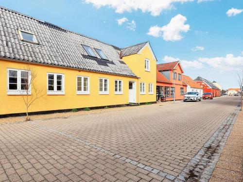 a street with a yellow house and a car on the road at 5 person holiday home in Ålbæk-By Traum in Ålbæk