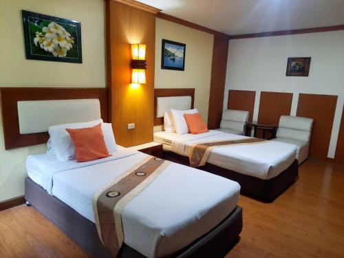 a hotel room with two beds with orange pillows at Siam Boutique Hotel โรงแรมสยามบูทีค in Buriram