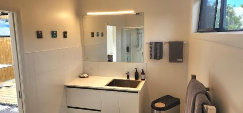 ein Bad mit einem Waschbecken und einem Spiegel in der Unterkunft Kiwiblue in Kerikeri
