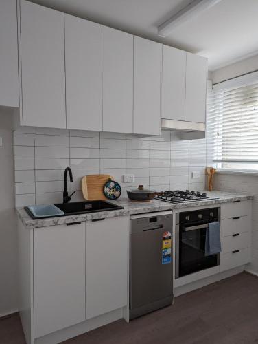 una cucina con armadi bianchi e piano cottura di Apartment a Melbourne