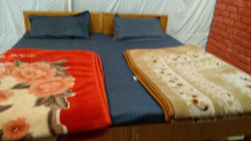two beds with blue and red sheets with flowers on them at Kandi Orchard Resort in Mussoorie