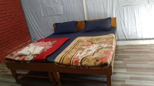 Kandi Orchard Resort في موسوري: سرير عليه وسائد زرقاء وبطانية
