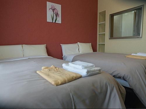 Dos camas con toallas encima. en Jisco Hotel Obama Onsen, en Obama
