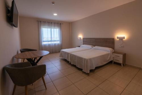 唐貝尼托的住宿－Hotel Tierra，酒店客房带一张床、一张桌子和椅子