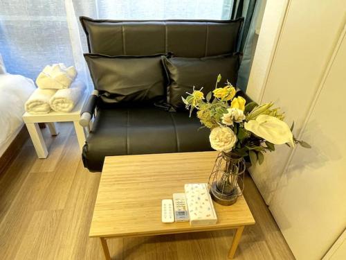 a living room with a leather chair and a table with a vase of flowers at Nishi-Ike Apartment Room 2 in Tokyo