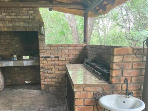an outdoor kitchen with a sink in a brick wall at Ivory Sands Safari Lodge in Marloth Park