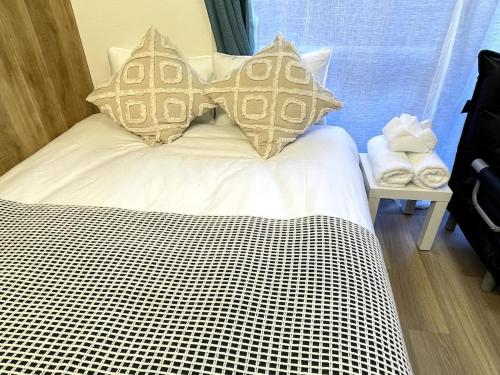 a bed with white sheets and pillows in a room at Nishi-Ike Apartment Room 2 in Tokyo