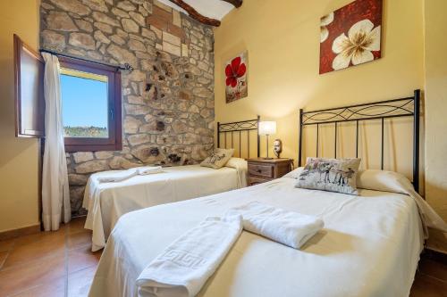 2 camas en una habitación con una pared de piedra en Mas de Sisco, en Flix