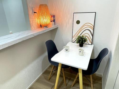 a white table with two chairs and a lamp and a picture at Nishi-Ike Apartment Room 2 in Tokyo