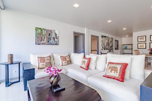 a living room with white furniture and red pillows at Kamala Beach Estate Resort - SHA Extra Plus in Kamala Beach