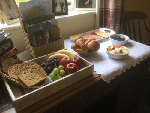 una mesa cubierta con una bandeja de pan y fruta en The Cottage, en Wadhurst