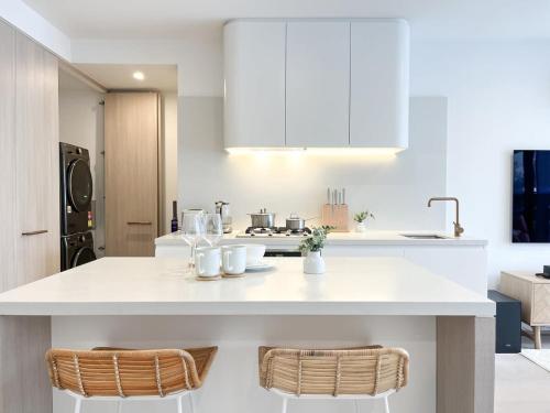 a kitchen with a white counter and two chairs at Modern Luxury 2B2B Sky Garden SmartTV in Glen Waverley