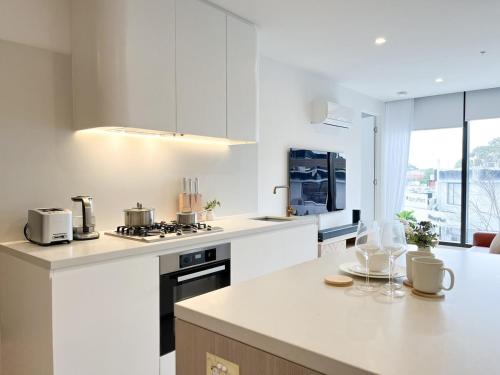 a kitchen with white cabinets and a counter top at Modern Luxury 2B2B Sky Garden SmartTV in Glen Waverley