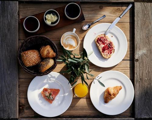 a wooden table topped with plates of food and bread at Hotel KÜGLERHOF in Tirolo