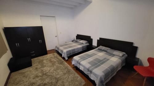 a bedroom with two beds and a red chair at La Casona Hospedaje in Lima
