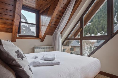 a bedroom with a bed and a large window at Luderna - Dúplex Val de Ruda C10 Estanh Redond in Baqueira-Beret