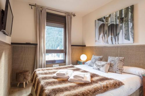 a bedroom with a large bed and a window at Luderna - Apartamento Dera Nhèu in Baqueira-Beret