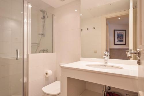 a white bathroom with a sink and a toilet at Luderna - Apartamento Dera Nhèu in Baqueira-Beret