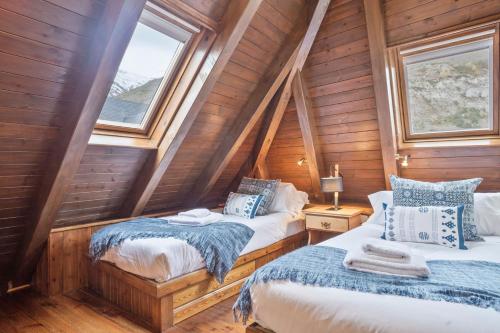 two beds in a room with wooden walls and windows at Luderna - Dúplex Nòdes II in Arties