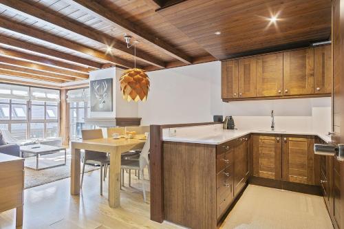 a kitchen with wooden cabinets and a dining table at Luderna - Apartamento Val de Ruda B14 Paulet in Baqueira-Beret