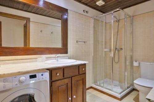 a bathroom with a washer and a sink and a shower at Luderna - Apartamento Val de Ruda B3 Entecada in Baqueira-Beret