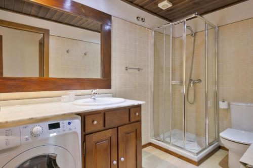 y baño con lavadora, lavamanos y ducha. en Luderna - Apartamento Val de Ruda B3 Entecada, en Baqueira Beret