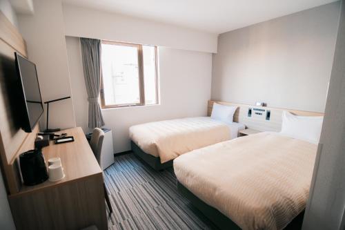 船橋市にあるクインテッサホテル千葉船橋のベッド2台とテレビが備わるホテルルームです。