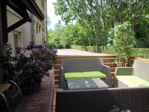 a patio with two chairs and a table and flowers at Logis Bagatelle - 51530 Dizy in Épernay