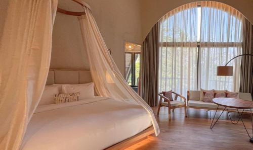 a bedroom with a white bed with a canopy at dusitD2 Khao Yai in Mu Si