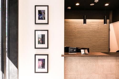 a white wall with framed pictures on it at WAYFARER Matsu in Osaka