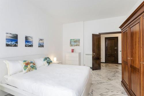 um quarto branco com uma cama e um armário de madeira em Charming Family Apartment by Wonderful Italy em Gênova