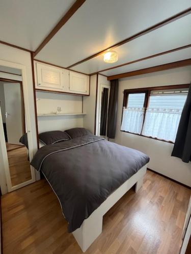 a bedroom with a large bed in a tiny house at Chalet in bosrijke omgeving op chaletpark Kempenbos naast Duc de Brabant voor 2-3-4-5 personen in Diessen