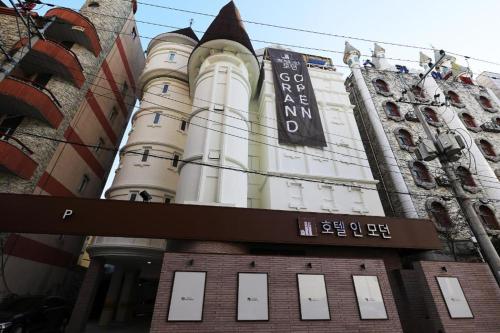 a tall white building with a sign on it at Hotel In Modern in Cheongju