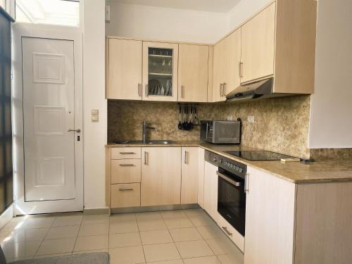 a kitchen with wooden cabinets and a sink and a stove at Lagada Resort in Makry Gialos