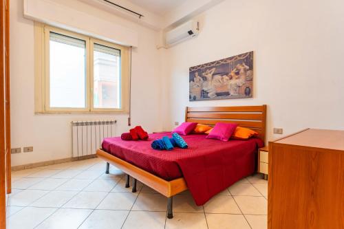 Schlafzimmer mit einem Bett mit roter Bettwäsche und bunten Kissen in der Unterkunft Casa Rosa in Sestu