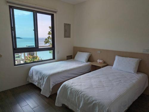 2 camas en una habitación con ventana grande en Ran Ran 29 Guest House en Beigan