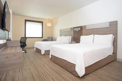 a hotel room with two beds and a flat screen tv at Holiday Inn Express Guadalajara Iteso, an IHG Hotel in Guadalajara