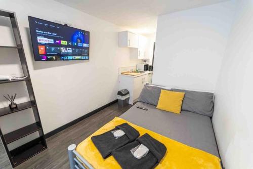 una piccola camera da letto con un letto con una coperta gialla di STAY SA Cosy equipped studios available 10 mins from the city! Free WIFI &50" SMART TV's! a Birmingham