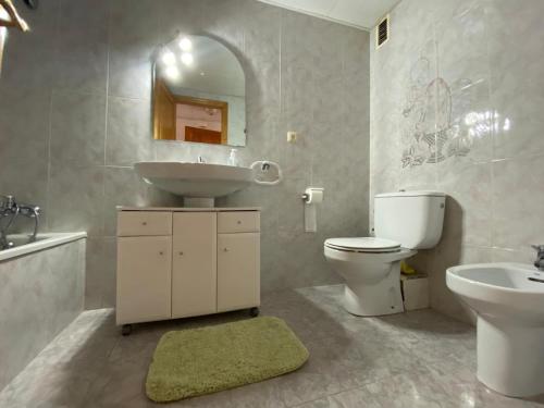 een badkamer met een wastafel, een toilet en een spiegel bij Apartamentos Ancosta in Peñíscola
