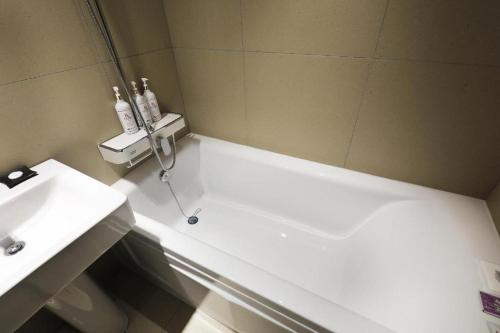 a bathroom with a white tub next to a sink at Hotel In Modern in Cheongju
