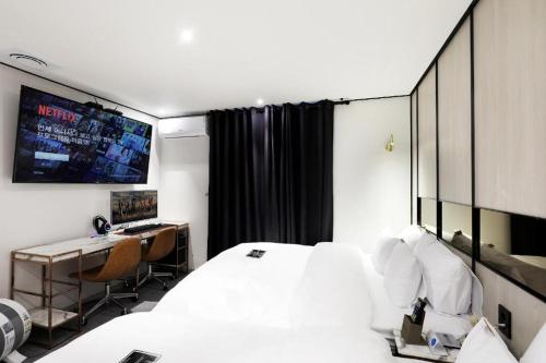 a bedroom with a bed and a desk and a television at Hotel In Modern in Cheongju