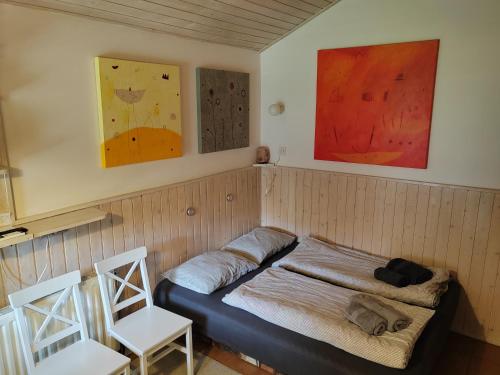 een kamer met een bed met 2 stoelen en schilderijen bij Cottage Barbara in Škofja Loka