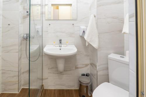 a white bathroom with a sink and a toilet at Supreme Victoria in Varna City
